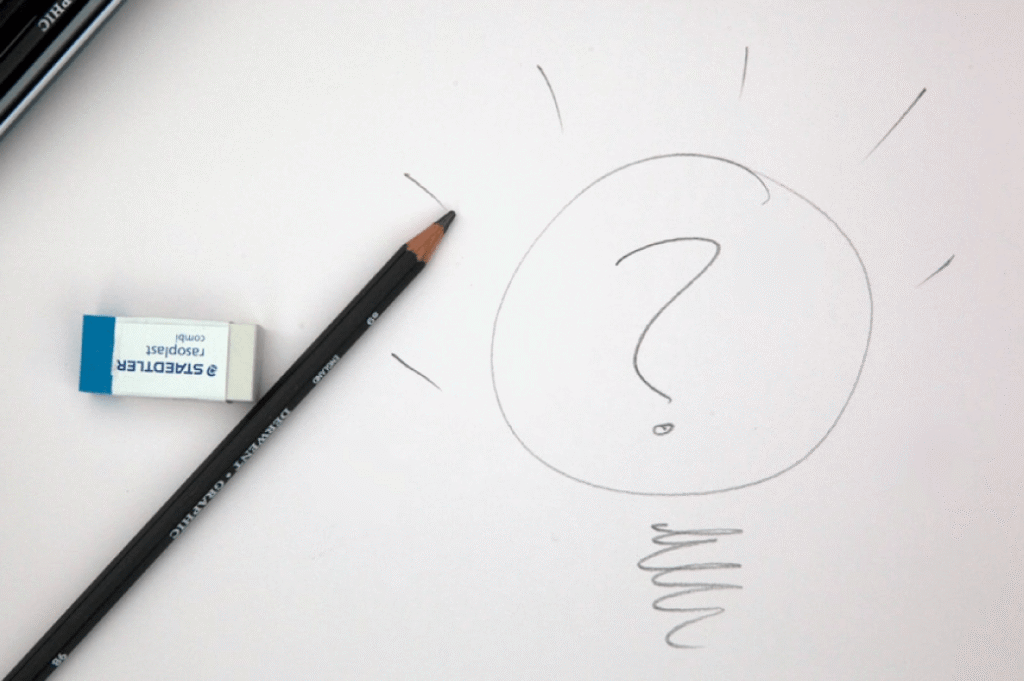 Image of a pencil and eraser on white paper with a hand drawn lightbulb with question mark